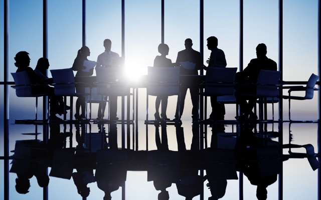 Silhouetted advisory team meeting around a boardroom table